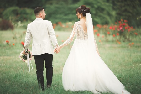 Romantic, fairytale, happy newlywed couple hugging and kissing in a park, trees in backgroundの写真素材