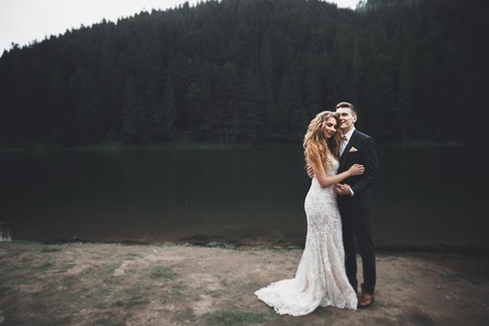 Beautiful gorgeous bride posing to groom and having fun, luxury ceremony at mountains with amazing...