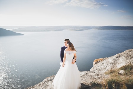 Wedding couple kissing and hugging on rocks near blue seaの写真素材