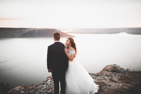 Wedding couple, groom, bride posing near sea on sunsetの写真素材