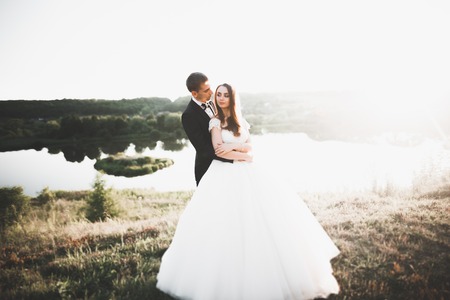 Newly married couple running and jumping in park while holding handsの写真素材