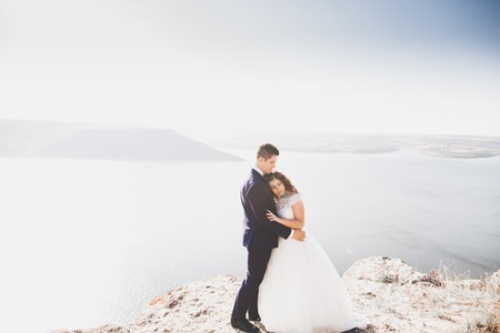 Elegant stylish happy wedding couple, bride, gorgeous groom on the background of sea and skyの写真素材