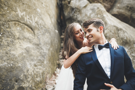 Happy wedding couple kissing and hugging near a high cliffの写真素材