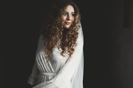 Gorgeous bride in robe posing and preparing for the wedding ceremony face in a roomの写真素材