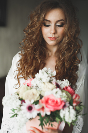 Gorgeous bride in robe posing and preparing for the wedding ceremony face in a roomの写真素材