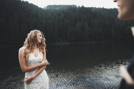 Beautifull wedding couple kissing and embracing near mountain with perfect viewの写真素材