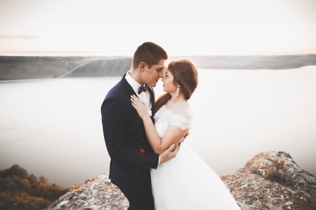 Elegant stylish happy wedding couple, bride, gorgeous groom on the background of sea and skyの写真素材