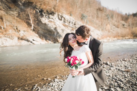 Elegant stylish happy brunette bride and gorgeous groom on the background of a beautiful river in...