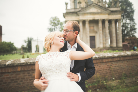 Beautiful fairytale newlywed couple hugging near old medieval castleの写真素材