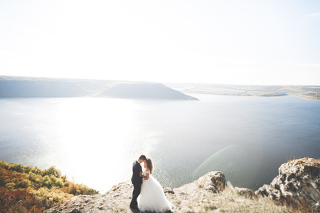 Elegant stylish happy wedding couple, bride, gorgeous groom on the background of sea and skyの写真素材