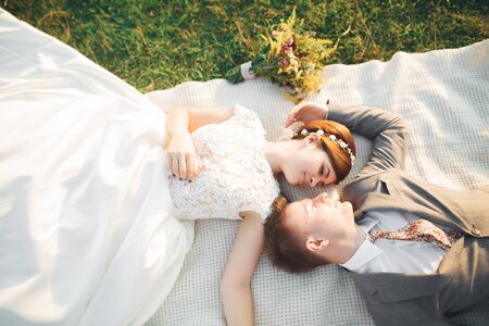 Wedding, beautiful romantic bride and groom kissing, embracing at sunsetの写真素材