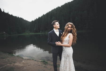 Beautifull wedding couple kissing and embracing near mountain with perfect viewの写真素材