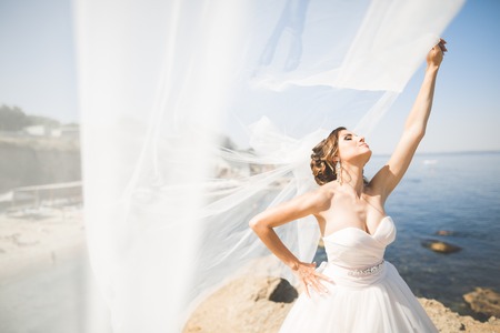 Beautiful young bride with bridal bouquet posing on the background seaの写真素材