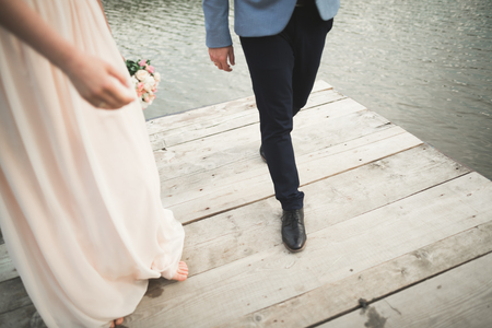 Charming bride, elegant groom on landscapes of mountains and sunset at lake. Gorgeous wedding coupleの写真素材