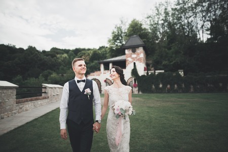 Lovely happy wedding couple, bride with long white dress posing in beautiful cityの写真素材