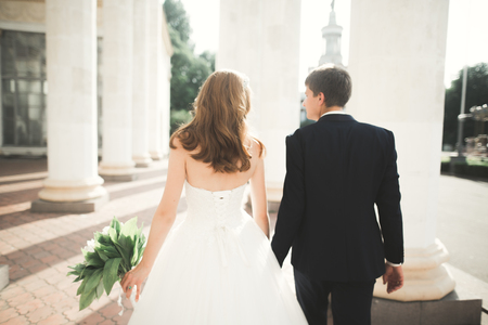 Lovely happy wedding couple, bride with long white dress posing in beautiful cityの写真素材