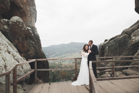 Wedding couple in love kissing and hugging near rocks on beautiful landscapeの写真素材