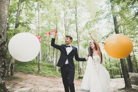 Young funny happy wedding couple outdoors with ballonsの写真素材