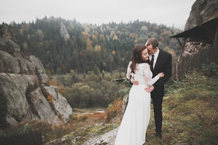 Wedding couple in love kissing and hugging near rocks on beautiful landscapeの写真素材