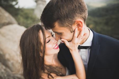 Happy wedding couple kissing and hugging near a high cliffの写真素材