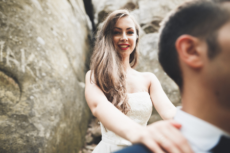 Happy wedding couple kissing and hugging near a high cliffの写真素材