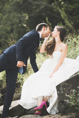 Elegant stylish happy brunette bride and gorgeous groom on the background of a beautiful river in the mountainsの写真素材