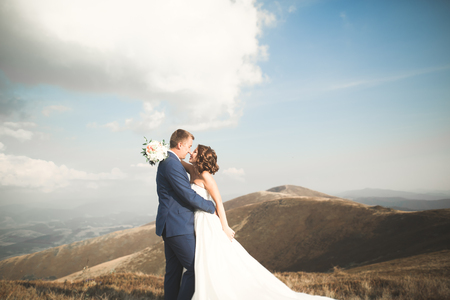 Beautifull wedding couple kissing and embracing near mountain with perfect viewの写真素材