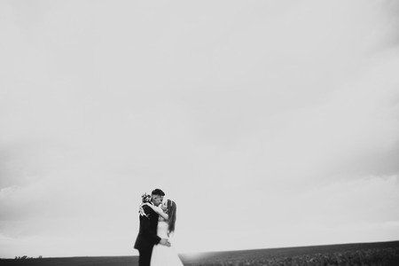 groom is holding and kissing his bride on the background sunsetの写真素材