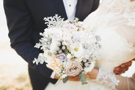Romantic, fairytale, happy newlywed couple hugging and kissing in a park, trees in background