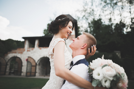 Lovely happy wedding couple, bride with long white dress posing in beautiful cityの写真素材