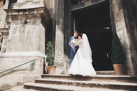 Lovely happy wedding couple, bride with long white dress posing in beautiful cityの写真素材