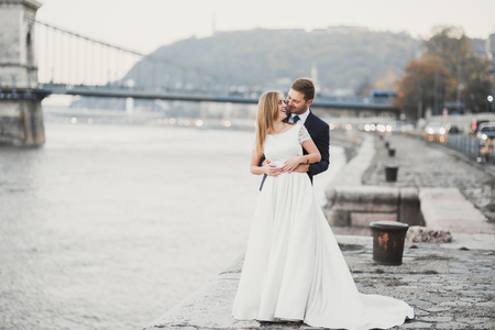 Elegant stylish happy blonde bride and gorgeous groom on the background of a beautiful river in the mountainsの写真素材