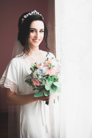 Gorgeous bride in robe posing and preparing for the wedding ceremony face in a roomの写真素材