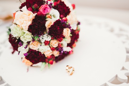 Beautiful toned picture with wedding rings against the background of a bouquet of flowers