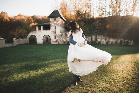 Romantic, fairytale, happy newlywed couple hugging and kissing in a park, trees in backgroundの写真素材