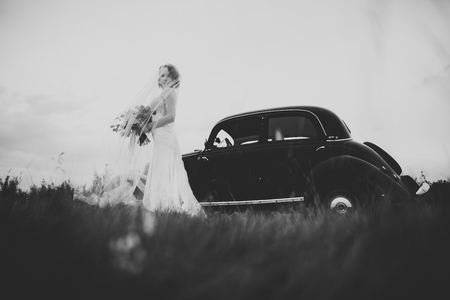 Happy bride in the retro car posing on her weeding dayの写真素材