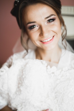 Gorgeous bride in robe posing and preparing for the wedding ceremony face in a roomの写真素材