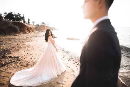 Wedding couple kissing and hugging on rocks near blue seaの写真素材