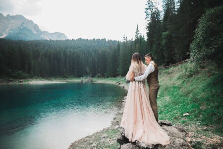 Wedding couple on the nature is hugging each other near a beautiful lake in the mountains.....