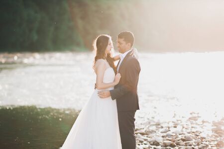 Wedding couple, groom and bride hugging, outdoor near river.の写真素材