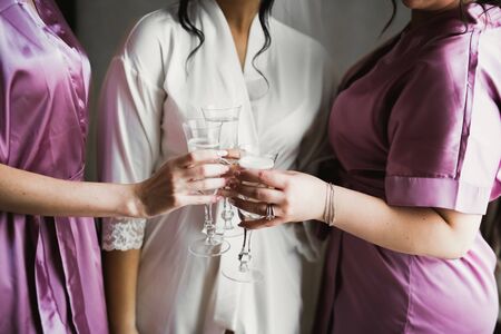 Photo bride with her friends drinking champagne from glassesの写真素材