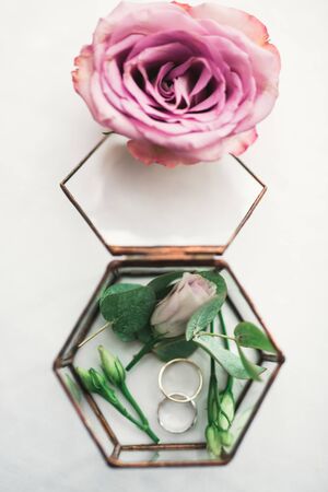 Beautiful toned picture with wedding rings against the background of a bouquet of flowers.の写真素材