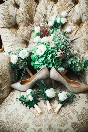 Pair of elegant and stylish bridal shoes and a bouquet of roses and other flowers.の写真素材