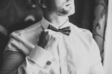Grooms morning preparation. Handsome man getting dressed and preparing for the wedding.の写真素材