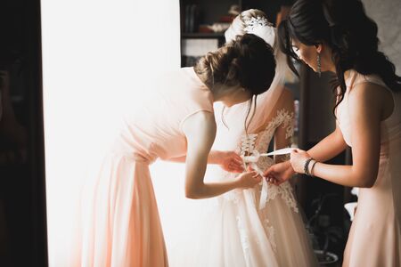 Hands of bridesmaids on bridal dress. Happy marriage and bride at wedding day conceptの写真素材