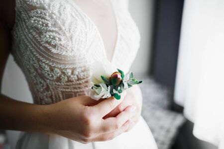 Beautiful luxury bride in elegant white dress holds bouquet of flowers in the hands.