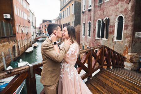 Romantic, fairytale, happy newlywed couple hugging and kissing in a park, trees in backgroundの写真素材