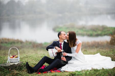 Beautiful bride and groom embracing and kissing on their wedding day outdoorsの写真素材