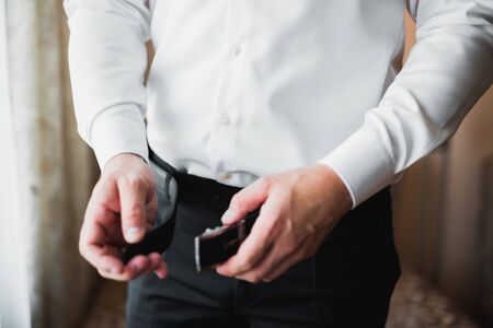Grooms morning preparation. Handsome man getting dressed and preparing for the wedding.