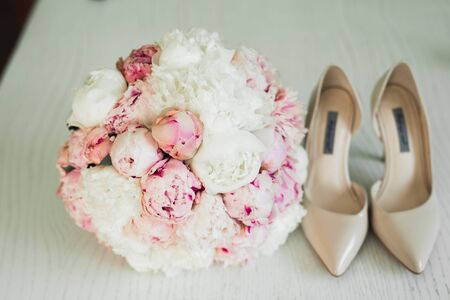 Pair of elegant and stylish bridal shoes with a bouquet with roses and other flowers.の写真素材